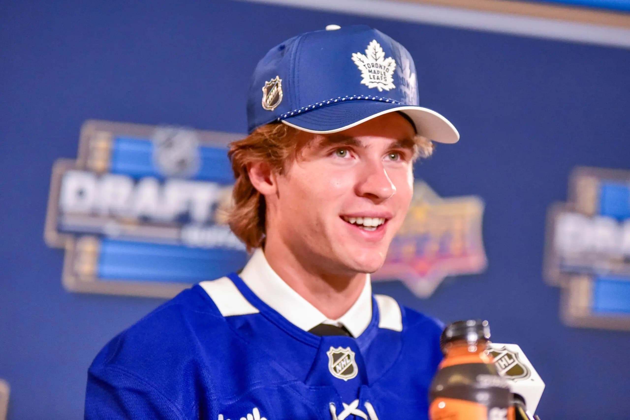 NHL first-round draft pick Gavin McKenna wearing a Maple Leafs baseball cap and hockey jersey.